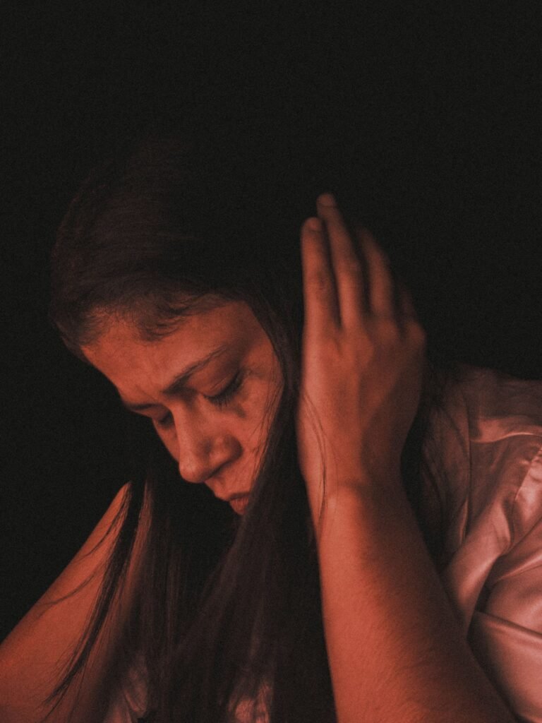 Mulher com expressão facial triste e olhar baixo, representando sintomas emocionais da depressão.