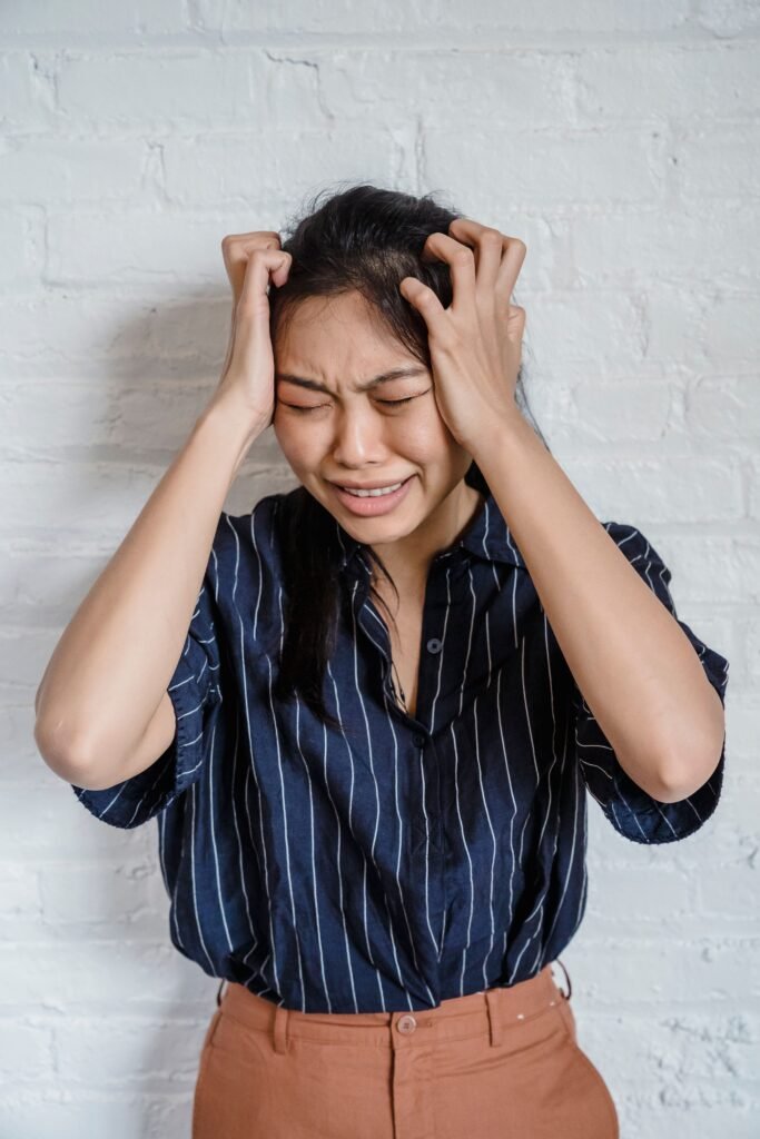 Mulher em estado de forte tensão emocional, com as mãos nos cabelos e expressão de nervosismo, sugerindo sofrimento psicológico, angústia e possível sensação de sobrecarga ou descontrole emocional.